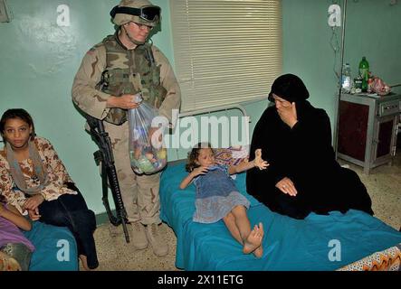 Un soldat de la 1re division de cavalerie, qui assure la sécurité des convois pour la mission des affaires civiles, aide à distribuer des jouets à l'hôpital pour enfants de Bagdad. env. 27 juin 2004 Banque D'Images