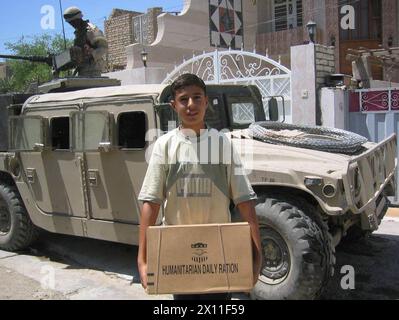 Après plusieurs jours de combats dans l'est de Bagdad, des soldats du 2e bataillon, du 8e régiment de cavalerie de la 1re division de cavalerie distribuent des rations d'aide humanitaire aux habitants de Sadr City CA. 20 août 2004 Banque D'Images