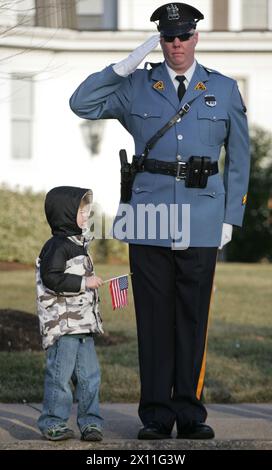 Hero Homecoming : un policier salue la procession pour le sergent Christopher R. Hrbek, 25 ans, natif de Westwood, N.J., 21 janvier 2010. Il a été escorté de la base aérienne de Douvres, Del., devant les rues bordées de gens agitant des drapeaux américains à Beckers Funeral Home. Banque D'Images