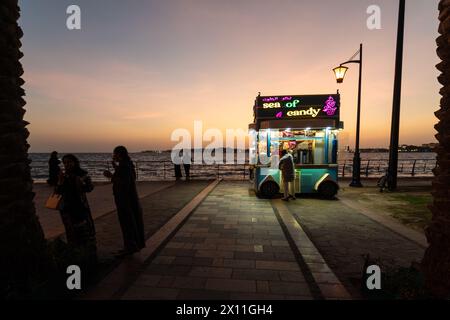 Djeddah, Arabie Saoudite - janvier 30 2023 : les gens apprécient le crépuscule à la Corniche Al-Hamra avec un stand de bonbons au bord de la mer rouge en Arabie Saoudite. Banque D'Images