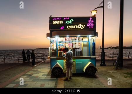 Djeddah, Arabie Saoudite - janvier 30 2023 : les gens apprécient le crépuscule à la Corniche Al-Hamra avec un stand de bonbons au bord de la mer rouge en Arabie Saoudite. Banque D'Images