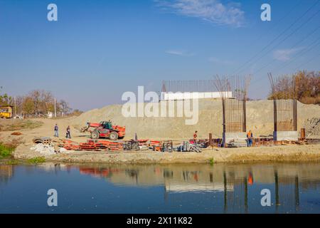 Piliers de pont en béton armé en construction de l'autre côté de la rivière, construction de béton moderne de poteaux qui soutiennent le pont routier. Équipe Banque D'Images