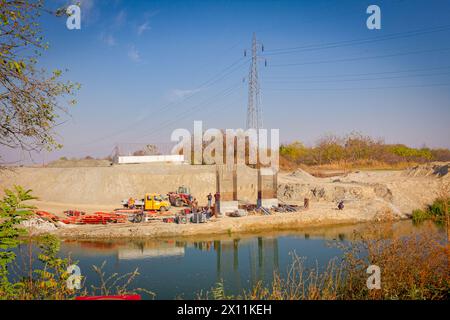 Piliers de pont en béton armé en construction de l'autre côté de la rivière, construction de béton moderne de poteaux qui soutiennent le pont routier. Équipe Banque D'Images