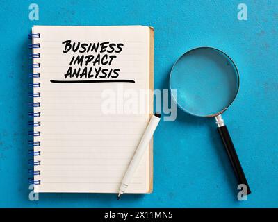 Analyse de l'impact sur l'entreprise manuscrite sur un ordinateur portable avec une loupe. Stratégie commerciale et concept de planification. Banque D'Images