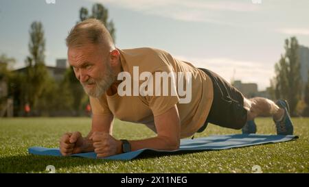 Vieil homme caucasien dans la ville de stade d'entraînement d'exercice de planche à l'extérieur de l'effort de contrainte de forme physique athlète santé musclé bodybuilder de pose physique Banque D'Images