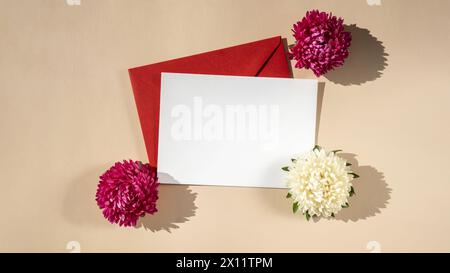 Belles petites fleurs blanches sur enveloppe rouge postale sur fond beige, espace de copie de note de papier vide pour le texte, printemps, carte de voeux pour les vacances. Concept de livraison de fleurs Banque D'Images