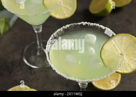 Délicieux cocktail Margarita avec des glaçons dans des verres et citron vert sur une table grise, gros plan Banque D'Images