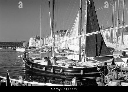 Deux garçons pêche et Yachts historiques en bois dans le Vieux Port Saint Tropez ou St Tropez Var Côte d'Azur ou Côte d'Azur France. Image vintage ou historique c1960 Banque D'Images