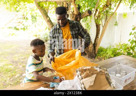 Père et fils afro-américains trient les matières recyclables dans la cour arrière à la maison Banque D'Images