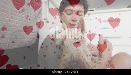 Image de coeur emojis sur femme caucasienne heureuse avec chien Banque D'Images