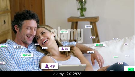 Image de barres de notification sur couple caucasien relaxant et regardant l'image sur tablette numérique Banque D'Images