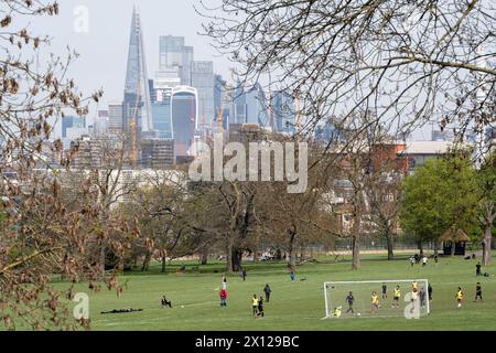 Avec les gratte-ciel de la City de Londres, le quartier financier de la capitale, au loin, les équipes de jeunes juniors jouent un match de football un samedi matin à Ruskin Park, un espace vert en pente du sud de Londres dans la banlieue sud de Londres, le 13 avril 2024, à Lambeth, Londres, Angleterre. Banque D'Images