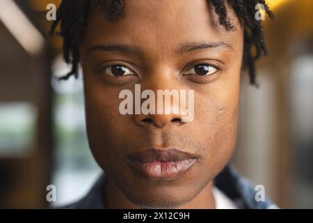Homme afro-américain avec de courts dreadlocks regardant la caméra dans un bureau d'affaires moderne Banque D'Images