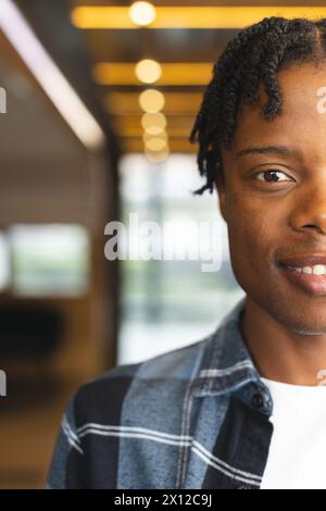 Homme afro-américain debout à l'intérieur dans un bureau d'affaires moderne, regardant la caméra avec espace de copie Banque D'Images