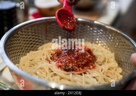 Ajouter de la sauce gochujang aux nouilles froides Banque D'Images
