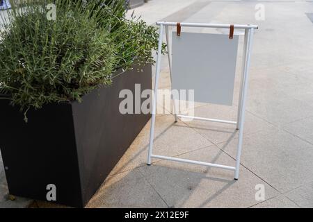 Modèle blanc blanc blanc de planche de support de publicité extérieure. Panneau de signalisation de rue transparent placé près de la salle à manger extérieure d'un restaurant. Backgroun Banque D'Images