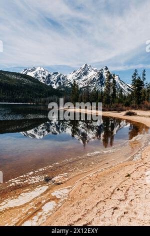 Montagnes de Sawtooth reflétées dans l'eau du lac alpin avec plage de sable Banque D'Images