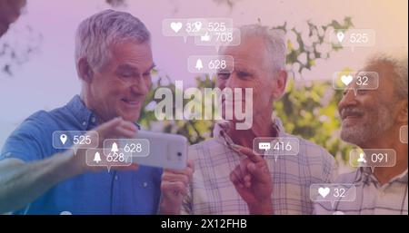 Image des icônes des médias sur les hommes âgés heureux divers utilisant un smartphone Banque D'Images