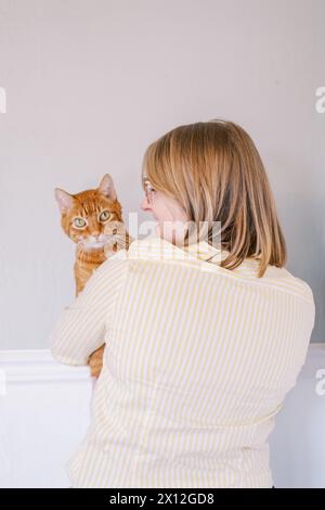 Femme avec des lunettes tenant chat tabby orange Banque D'Images
