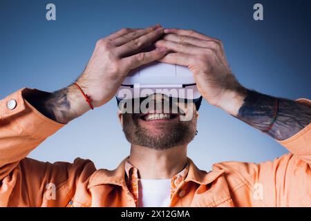 Un homme portant une chemise orange dans un cadre de studio, immergé dans une expérience de réalité virtuelle. Banque D'Images