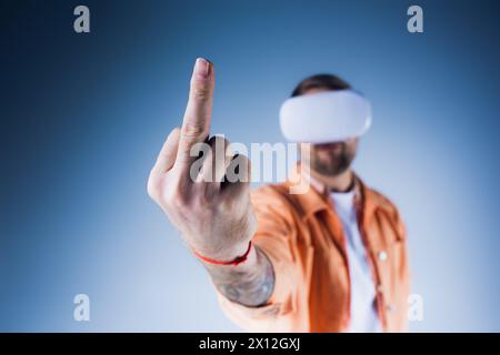 Un homme, les yeux bandés et portant un casque VR, pointe avec confiance vers une cible invisible dans un cadre de studio, le majeur Banque D'Images