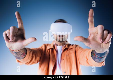 Un homme dans un casque VR, les yeux bandés avec un bandeau, fait en toute confiance le signe Vulcain dans un cadre de studio. Banque D'Images