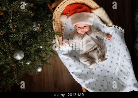 Le nouveau-né est couché dans un berceau, portant un chapeau de Père Noël. Banque D'Images