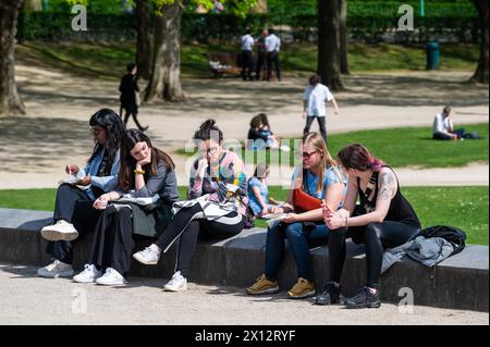 Etterbeek, Bruxelles, Belgique - 13 avril 2024 - personnes assises au soleil à la fontaine du parc du Cinquantenaire Banque D'Images