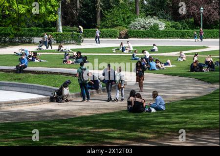 Etterbeek, Bruxelles, Belgique - 13 avril 2024 - personnes assises au soleil à la fontaine du parc du Cinquantenaire Banque D'Images