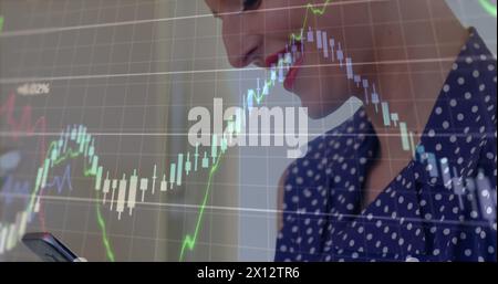 Image de plusieurs graphiques avec des chiffres changeants sur une femme caucasienne utilisant un smartphone Banque D'Images