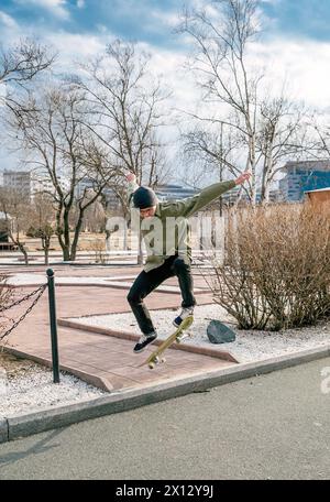 Jeune homme chevauchant une planche à roulettes faisant des tours et des sauts Banque D'Images