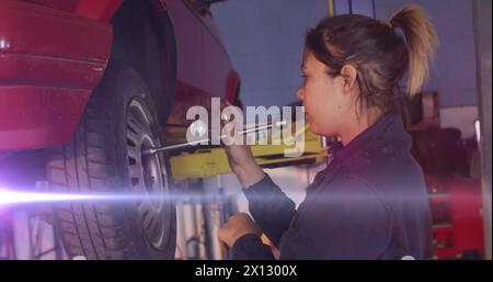 Image de taches lumineuses sur la femme biraciale réparant la voiture Banque D'Images