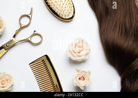Composition de pose plate avec différents outils de coiffeur et fleurs sur fond blanc Banque D'Images