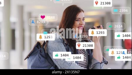 Image des icônes de médias sociaux et des numéros sur une femme caucasienne avec smartphone Banque D'Images