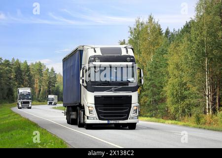 Trois semi-remorques blanches Volvo FH transportent des marchandises le long de l'autoroute 25 par une journée ensoleillée de début d'automne. Raasepori, Finlande. 8 septembre 2023. Banque D'Images