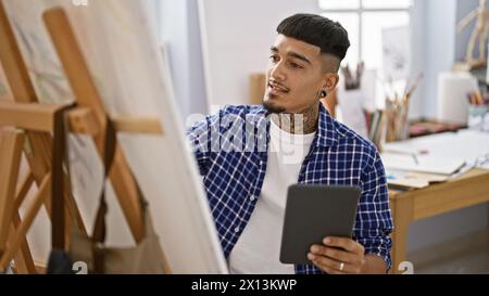 Beau jeune artiste latin sérieusement absorbé dans son passe-temps de dessin sur touchpad au studio d'art de l'université Snug Banque D'Images