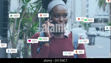 Image de plusieurs icônes de médias sociaux sur une femme afro-américaine parlant sur smartphone à l'extérieur. Réseau social et concept technologique Banque D'Images