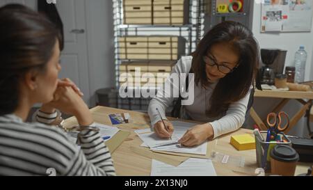 Deux femmes enquêtent sur des documents et des preuves dans un poste de police intérieur. Banque D'Images