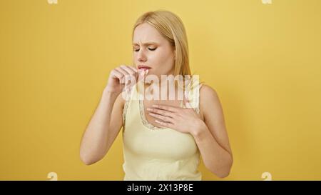 Une femme blonde toussant et se sentant malheureuse sur un fond jaune, représentant une maladie ou une allergie. Banque D'Images