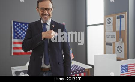 Homme barbu d'âge moyen montrant fièrement l'autocollant « j'ai voté » dans le cadre du collège électoral américain avec des drapeaux Banque D'Images