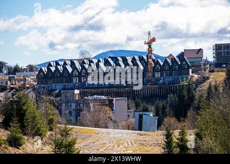 grue de construction sur fond d'une maison indigne par une journée ensoleillée parmi les montagnes. Immobilier et Banque D'Images