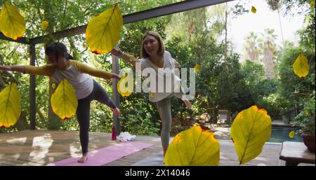 Icône de feuilles multiples tombant contre deux femmes asiatiques effectuant du yoga Banque D'Images