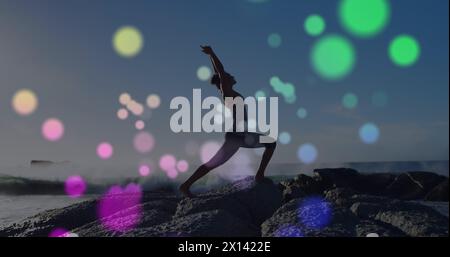 Image de lumières sur une femme caucasienne pratiquant le yoga sur la plage Banque D'Images