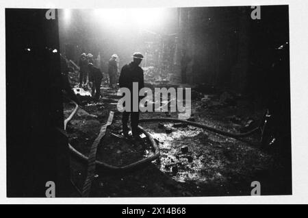 ACTEURS DE CINÉMA AFS : LE TOURNAGE DE 'L'HISTOIRE INÉDITE' AUX STUDIOS DE CINÉMA DE DENHAM, DENHAM, BUCKINGHAMSHIRE, ANGLETERRE, ROYAUME-UNI, 1941 - pendant le tournage du film de la Two Cities film Company 'Unpublished Story', tourné aux studios Denham, des hommes du service d'incendie auxiliaire d'Uxbridge déposent leurs tuyaux le long d'une 'rue' imbibée d'eau. Le film est réalisé par Harold French et met en vedette Richard Greene et Valerie Hobson. Il se déroule pendant le Blitz sur les quais de Londres en 1940 Banque D'Images