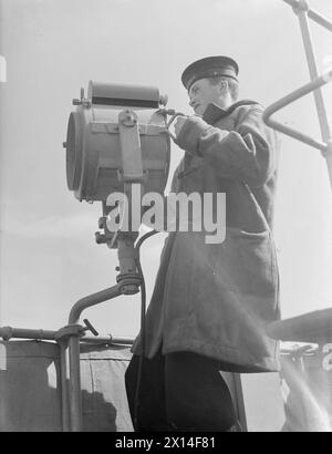 LES HOMMES DE LA CORVETTE BRITANNIQUE, HMS VERVAIN, EN SERVICE ACTIF. 9-10 JUILLET 1942. - Un signaleur avec le projecteur de signalisation Banque D'Images