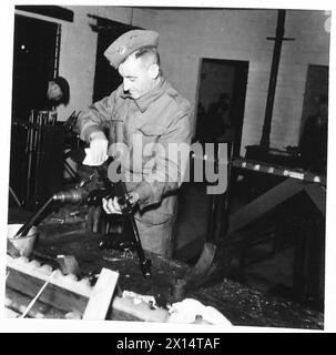 LES ACTIVITÉS DES INGÉNIEURS ÉLECTRICIENS ET MÉCANIQUES ROYAUX - Un instructeur de formation aux armes assiste à un pistolet Tommy dans un atelier REME British Army Banque D'Images