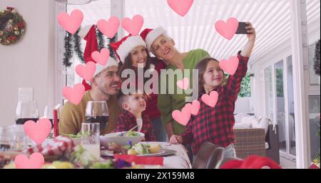 Image de cœurs sur la famille caucasienne heureuse prenant selfie Banque D'Images