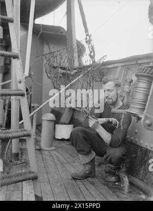 En juillet 1943, le HMT Stella Pegasi escorte le navire Pole Star tout en livrant des magasins et des fournitures aux équipages des phares autour de la côte. Les membres de l'équipage effectuaient des tâches sur le pont, y compris la fabrication d'un filet à poissons entre les montres. Banque D'Images