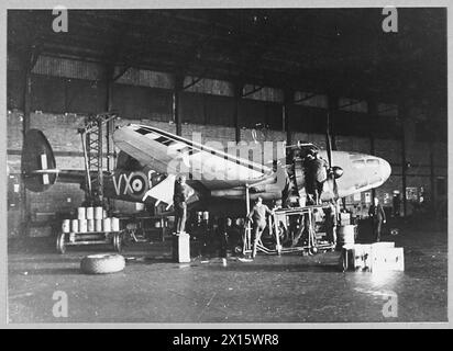 TROUVEZ L'ENNEMI, FRAPPEZ L'ENNEMI, PROTÉGEZ LA NAVIGATION. LA TRIPLE TÂCHE DU COMMANDEMENT CÔTIER. - (5797) quelques-uns des hommes qui gardent les avions du Coastal Command dans les airs. Un avion subissant des réparations majeures dans son hangar Royal Air Force Banque D'Images