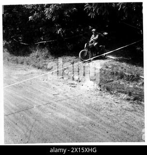 COURSE DE MOTO DE la 49TH DIVISION - après être descendu un chemin très délicat à travers un bois, ils émergent sur une piste de terre British Army, 21st Army Group Banque D'Images